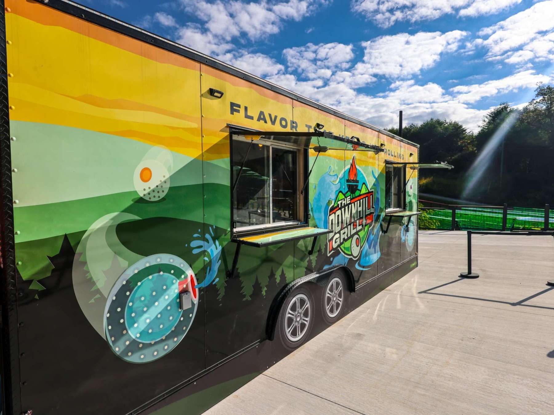 Colorful food truck with 'The Downhill Grill' logo parked outdoors.